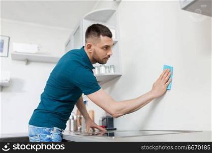 household and people concept - man with cloth cleaning wall at home kitchen. man with rag cleaning wall at home kitchen. man with rag cleaning wall at home kitchen