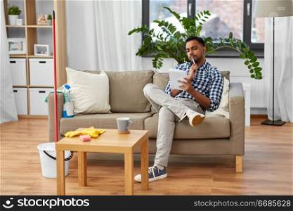 household and time management concept - indian man making to do list in notebook after home cleaning. indian man making to do list after home cleaning
