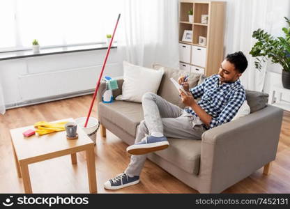 household and time management concept - indian man making to do list in notebook after home cleaning. indian man with to do list after home cleaning