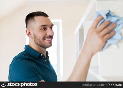 household, cleaning and people concept - man wiping shelf with cloth at home. man cleaning shelf with cloth at home. man cleaning shelf with cloth at home
