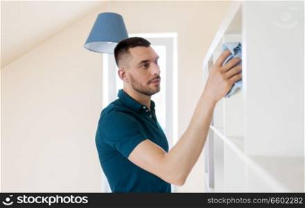 household, cleaning and people concept - man wiping shelf with cloth at home. man cleaning shelf with cloth at home