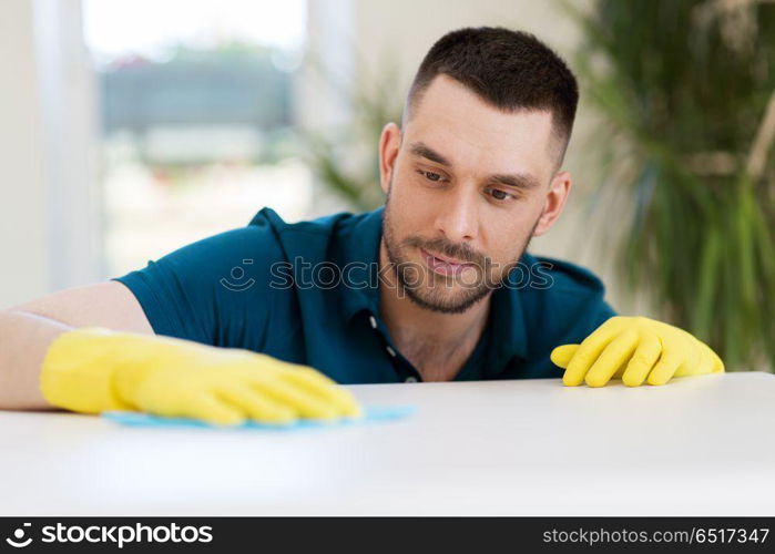 household, cleaning and people concept - man wiping table with cloth at home. man cleaning table with cloth at home. man cleaning table with cloth at home