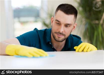 household, cleaning and people concept - man wiping table with cloth at home. man cleaning table with cloth at home. man cleaning table with cloth at home