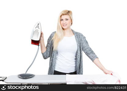 Household duties, taking care of clothes concept. Happy woman standing behind board holding iron about to do ironing. Happy woman holding iron about to do ironing