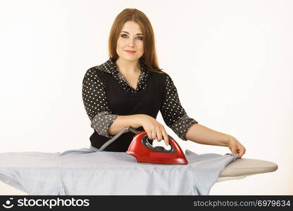 Household duties, taking care of clothes concept. Happy woman standing behind board ironing clothing. Happy woman doing ironing