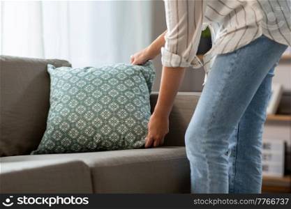 household, home improvement and cleaning concept - close up of woman arranging cushions on armchair and sofa. close up of woman arranging cushions at home