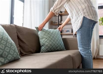 household, home improvement and cleaning concept - close up of woman arranging cushions on armchair and sofa. close up of woman arranging cushions at home