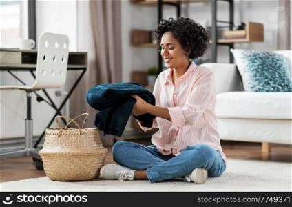 household, home improvement and cleaning concept - happy smiling young woman with blanket and wicker basket sitting on floor. happy woman with blanket and wicker basket at home