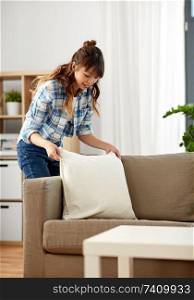 household, housework and cleaning concept - asian woman arranging sofa cushions at home. asian woman arranging sofa cushions at home