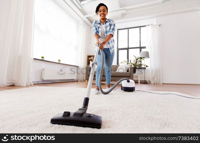 household, housework and cleaning concept - happy african american woman or housewife with vacuum cleaner at home. woman or housewife with vacuum cleaner at home