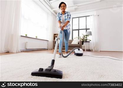 household, housework and cleaning concept - happy african american woman or housewife with vacuum cleaner at home. woman or housewife with vacuum cleaner at home