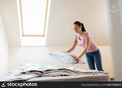 household, housework and cleaning concept - happy woman or housewife making bed at home. happy woman or housewife making bed at home. happy woman or housewife making bed at home