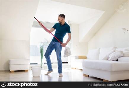 household, housework and people concept - happy man with mop and bucket cleaning floor and having fun at home. man with mop and bucket cleaning floor at home. man with mop and bucket cleaning floor at home