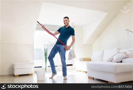 household, housework and people concept - happy man with mop and bucket cleaning floor and having fun at home. man with mop and bucket cleaning floor at home. man with mop and bucket cleaning floor at home