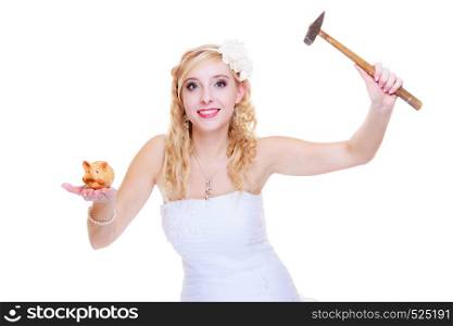 Household savings, cash after wedding concept. Bride wearing white dress trying to break piggy bank with hammer. Bride trying to break piggy bank with hammer