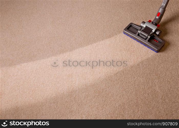 Housekeeper doing vacuum cleaning. Maid vacuuming the carpet. Carpet is dirty with cleaned area.