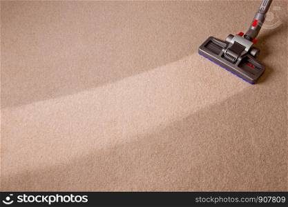 Housekeeper doing vacuum cleaning. Maid vacuuming the carpet. Carpet is dirty with cleaned area.