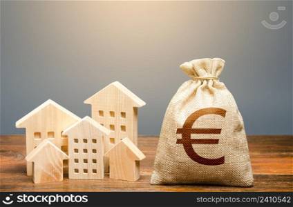 Houses and euro money bag. Investments in real estate and construction industry. Energy efficiency and costs for heating and home services. Community municipal budget.