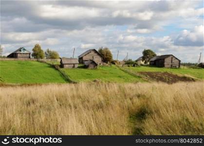 Houses, sheds and vegetable gardens in northern russian village, sunny autumn day