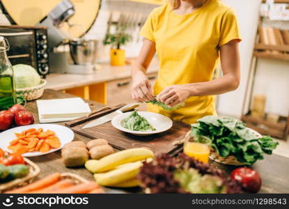 Housewife cooking on the kitchen, healthy bio food. Vegetarian diet, fresh vegetables and fruits on wooden table