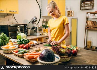 Housewife cooking on the kitchen, healthy organic food preparation. Vegetarian diet, fresh vegetables and fruits on wooden table. Housewife cooking, organic food preparation