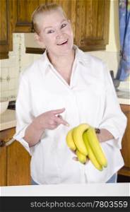 housewife in her kitchen shows with the index finger on a few bananas