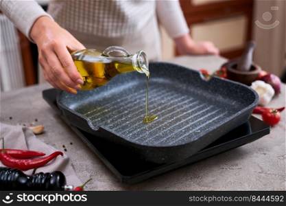 housewife pouring olive oil on hot frying pan at domestic kitchen.. housewife pouring olive oil on hot frying pan at domestic kitchen