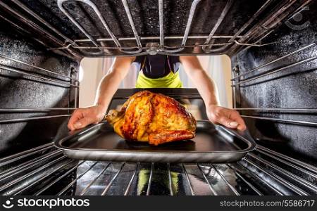 Housewife prepares roast chicken in the oven, view from the inside of the oven. Cooking in the oven.