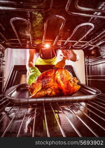 Housewife prepares roast chicken in the oven, view from the inside of the oven. Cooking in the oven.