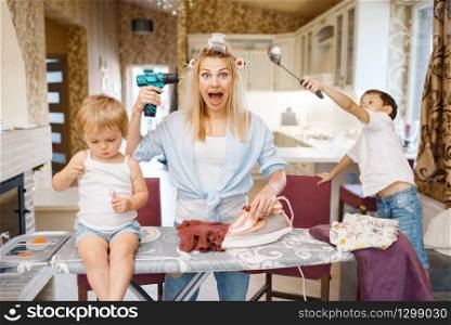 Housewife with kids having a good time on the kitchen. Woman with children playing at home together. Female person with daughter and son fooling around in their house