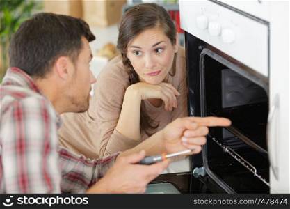 housewife with worker near oven in kitchen