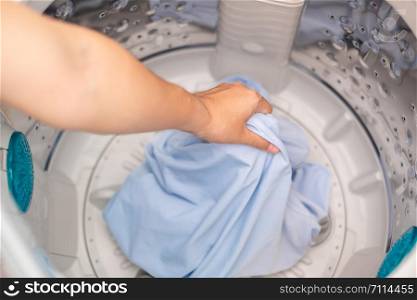 Housewife Woman hand holding clothes inside Washing Machine in laundry room