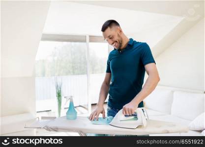 housework and household concept - man ironing shirt on iron board at home. man ironing shirt by iron at home. man ironing shirt by iron at home