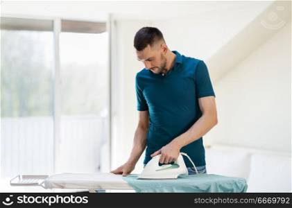 housework and household concept - man ironing shirt on iron board at home. man ironing shirt by iron at home. man ironing shirt by iron at home