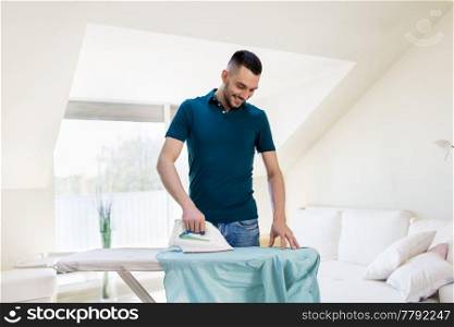 housework and household concept - man ironing shirt on iron board at home. man ironing shirt by iron at home