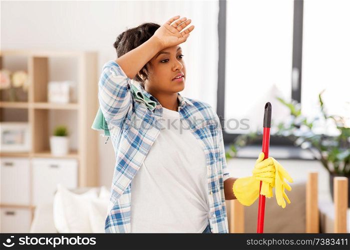 housework and housekeeping concept - tired african american woman or housewife with mop cleaning floor at home. tired african woman or housewife cleaning at home