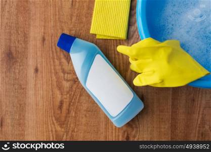 housework, housekeeping and household concept - basin with cleaning stuff on wooden background. basin with cleaning stuff on wooden background