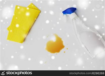 housework, housekeeping and household concept - cleaning rag, detergent spray and spilled stain on white background over snow. cleaning rag, detergent spray and spilled stain