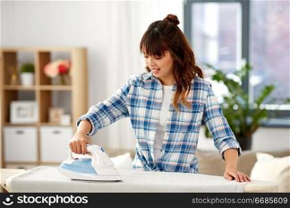housework, laundry and housekeeping concept - asian woman ironing bed linen on board at home. asian woman ironing bed linen at home