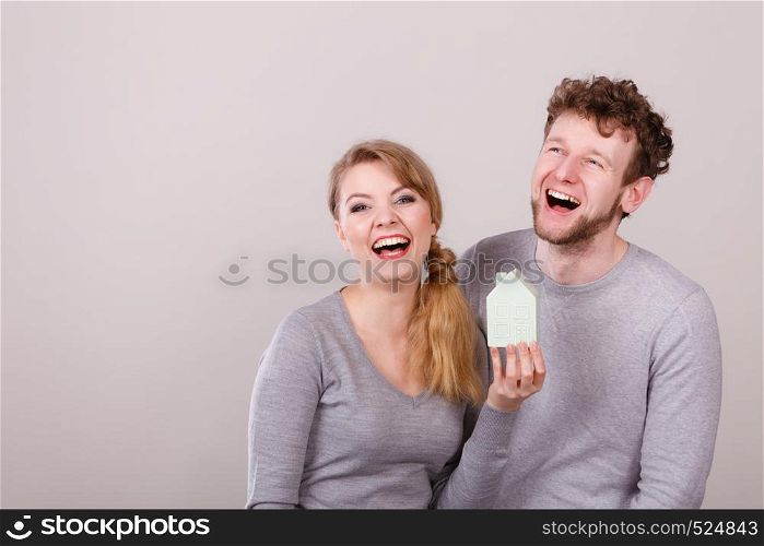 Housing family future mortgage finances concept. Cheerful young couple with house model. Youthful man and woman smiling with home symbol.. Cheerful young couple with house model.