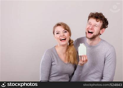 Housing family future mortgage finances concept. Cheerful young couple with house model. Youthful man and woman smiling with home symbol.. Cheerful young couple with house model.