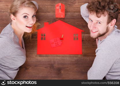 Housing finances real estate family future concept. Couple on floor with symbols. Man with lady next to home piggy bank models.. Couple on floor with symbols.