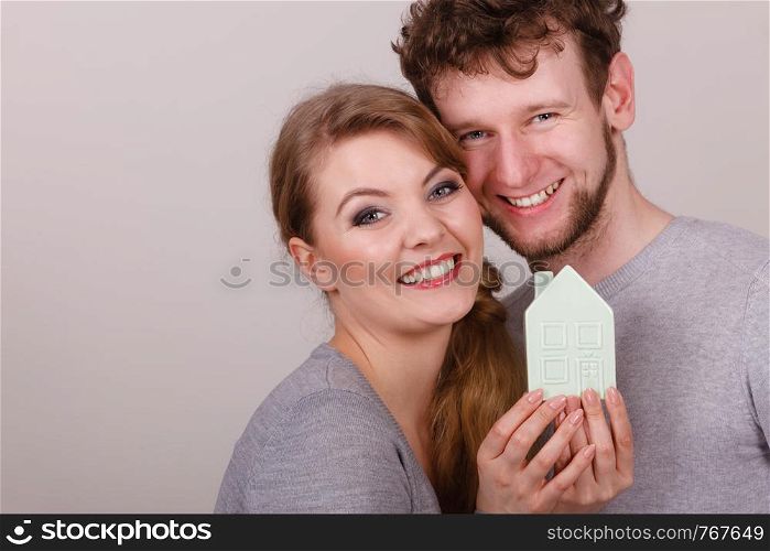 Housing property ownership marriage family future mortgage concept. Young enamoured pair showing house symbol. Man with lady presenting home model.. Young enamoured pair showing house symbol.