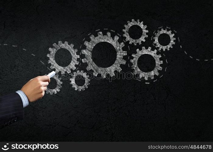 How it works. Close up of hand drawing gears mechanism with chalk