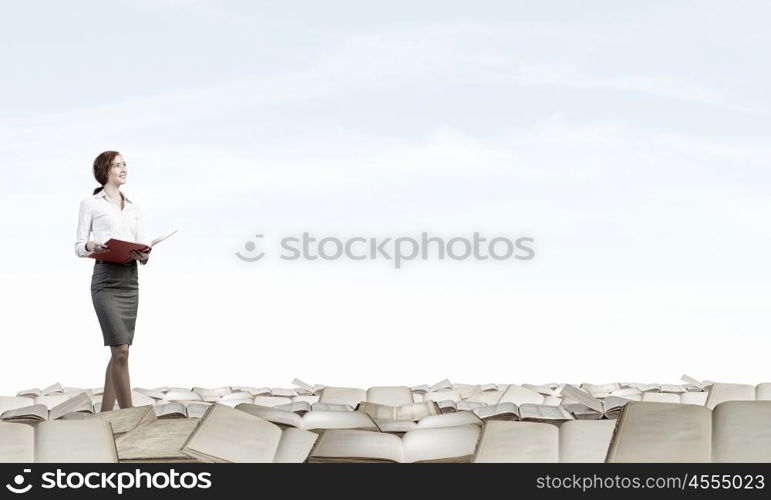 How much do you read. Pretty businesswoman walking on pile of old books