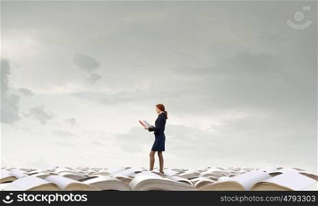How much do you read. Pretty businesswoman walking on pile of old books