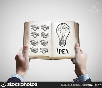 How to earn money. Opened book in male hands with financial ideas on pages