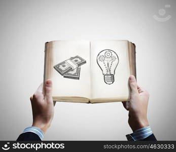 How to earn money. Opened book in male hands with financial ideas on pages