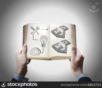 How to earn money. Opened book in male hands with financial ideas on pages