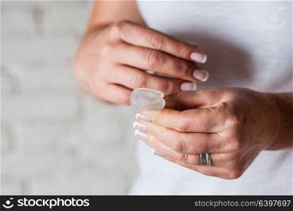 How to use menstrual cup in female hands. Woman holds flower and silicone hygiene cup, new device for minimize waste and preservation of the environment.. menstrual cup in female hands
